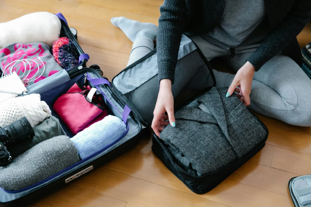 Traveler packing light suitcase with reusable items – sustainable travel tips for a more eco friendly vacation